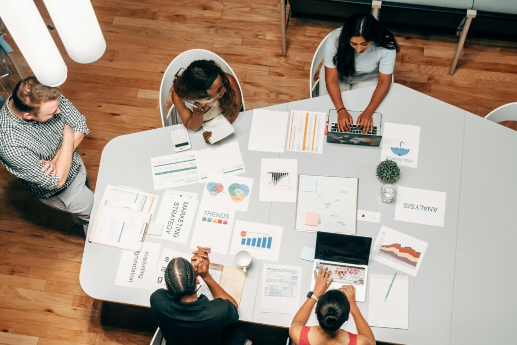 A diverse group working on marketing strategies with charts and laptops in an office setting.